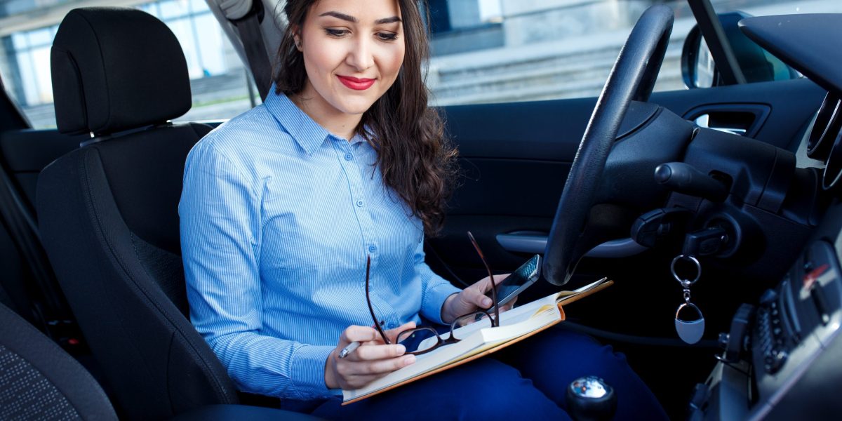 Businesswoman sitting in the car looking at her planner.